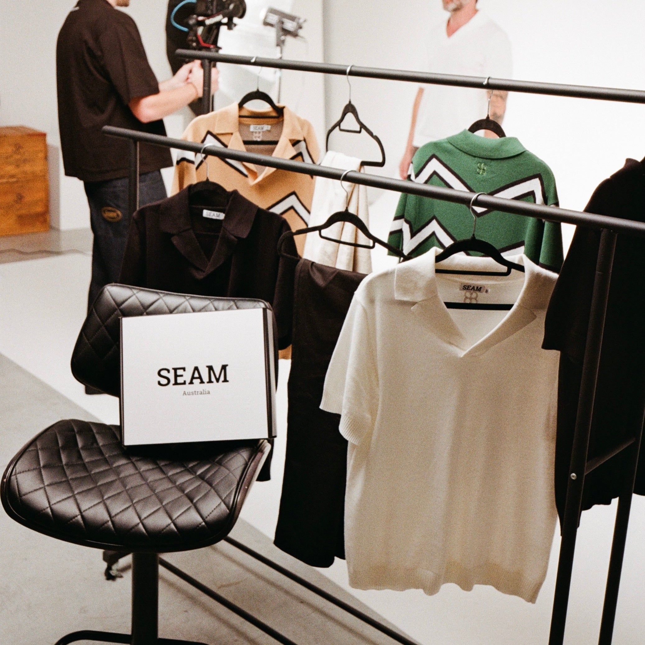 Man filming another man in a clothing store with 'SEAM' branding.