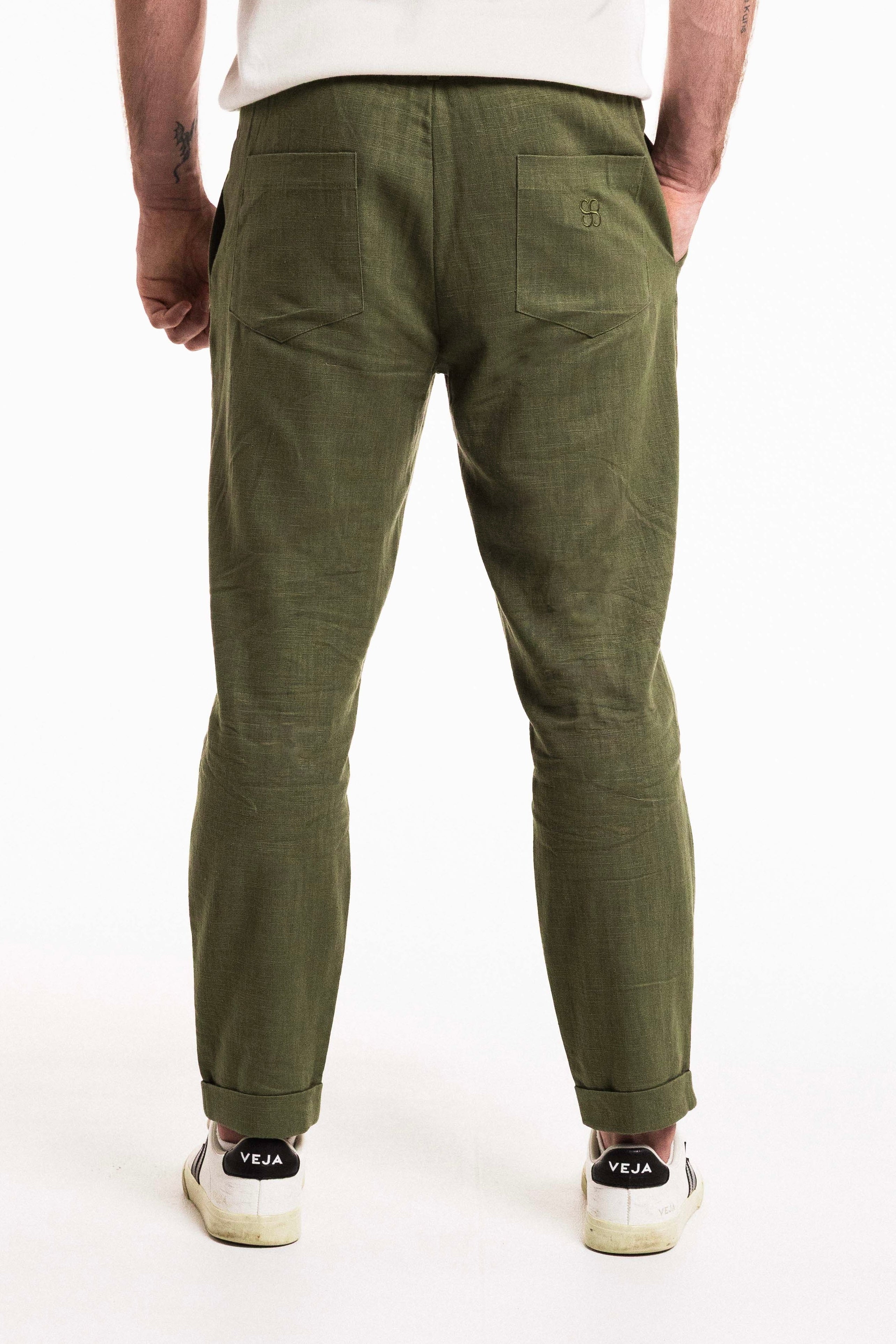 Back view of a man wearing Pleat Cuff Linen Trouser in olive, showcasing tailored design and functional pockets.