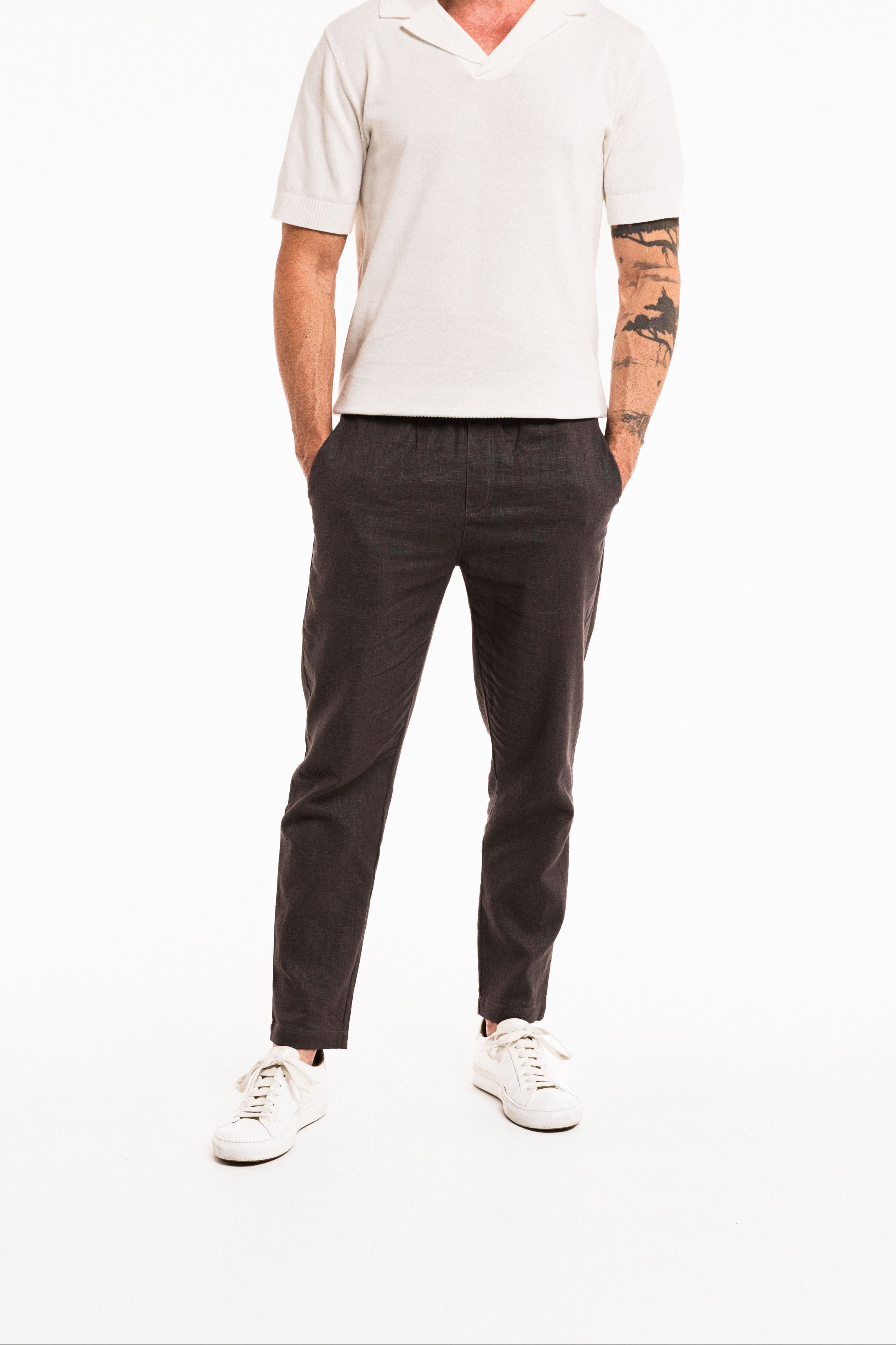 Person wearing a white shirt, black pants, and white sneakers on a white background
