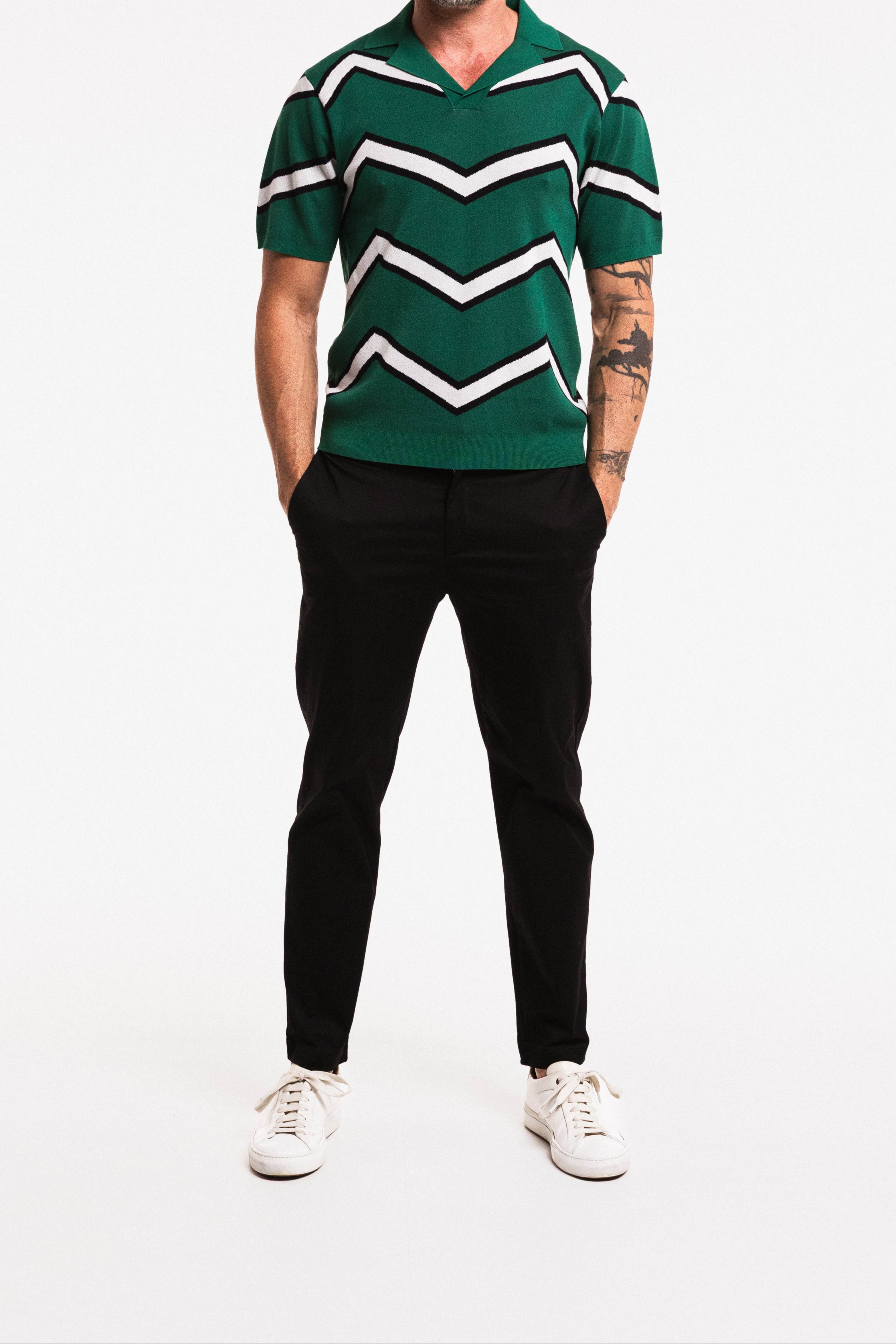 Man wearing a green and white striped shirt with black pants on a white background