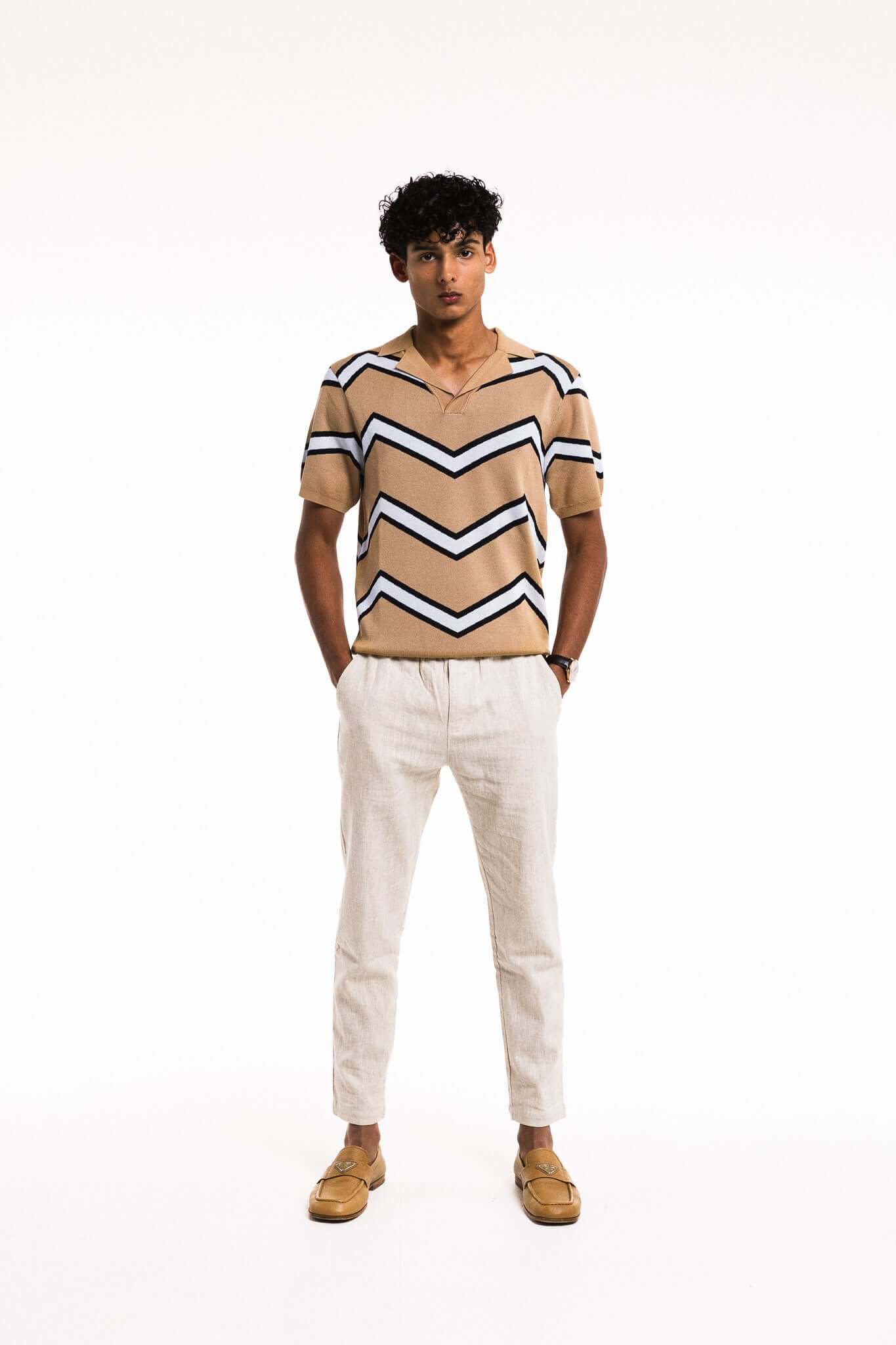 Model wearing a Chevron Zigzag Polo with bold stripes, paired with white trousers and casual shoes.
