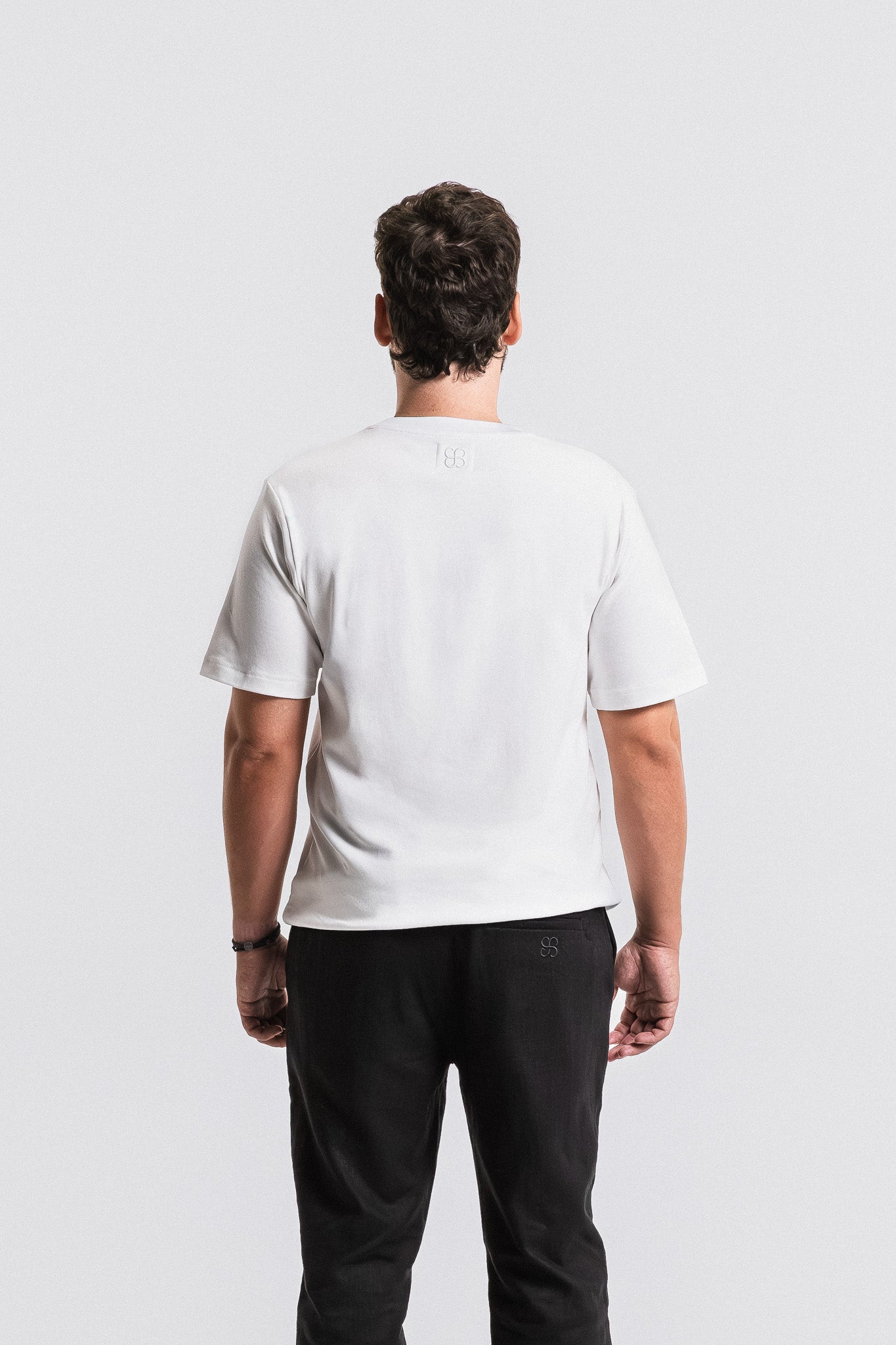Person wearing a white t-shirt and black pants on a plain background