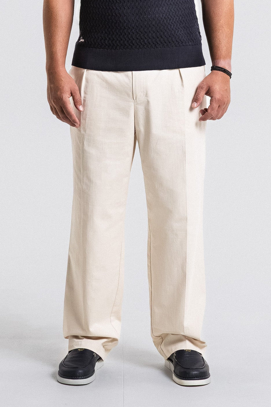 Person wearing beige pants and black shoes on a white background