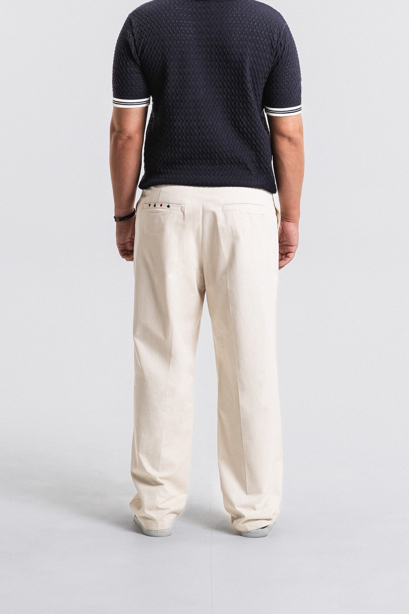 Person wearing a navy sweater and beige pants on a light gray background