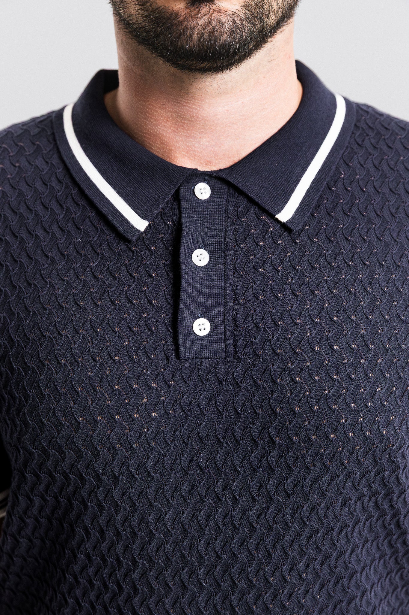Navy blue textured polo shirt with white trim worn by a person