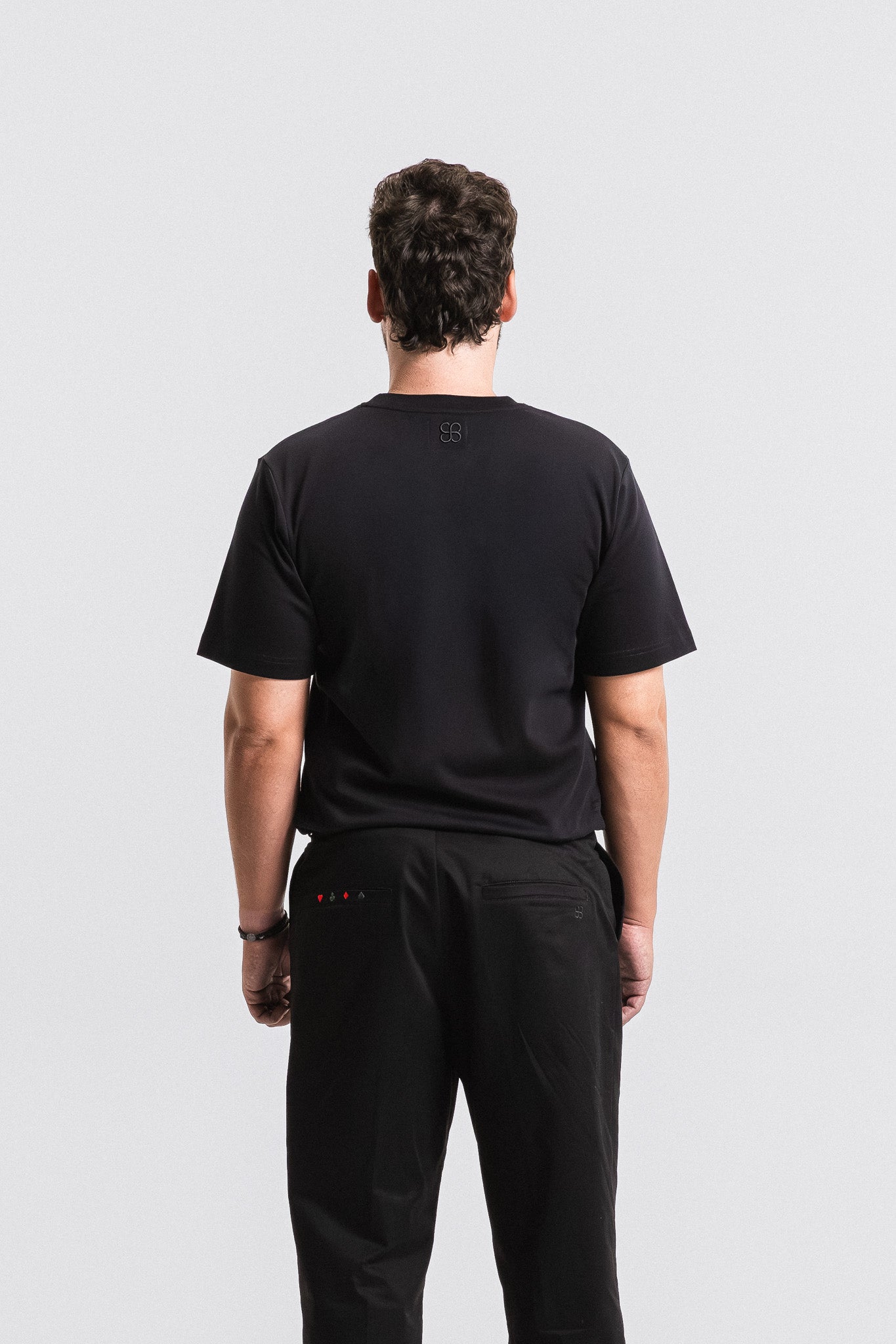 Person wearing a black t-shirt and pants on a light gray background