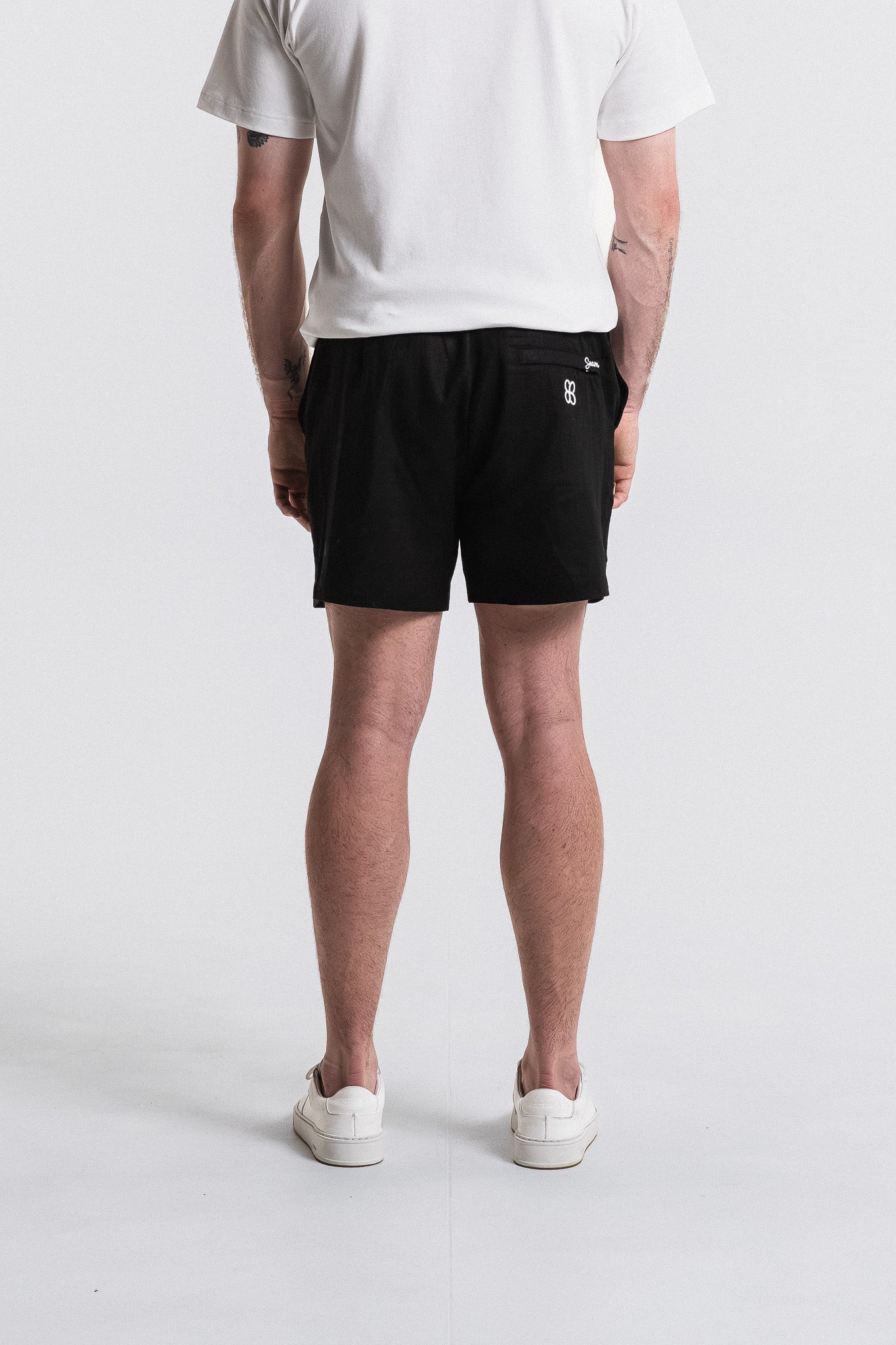 Person wearing black shorts with a logo on a white background