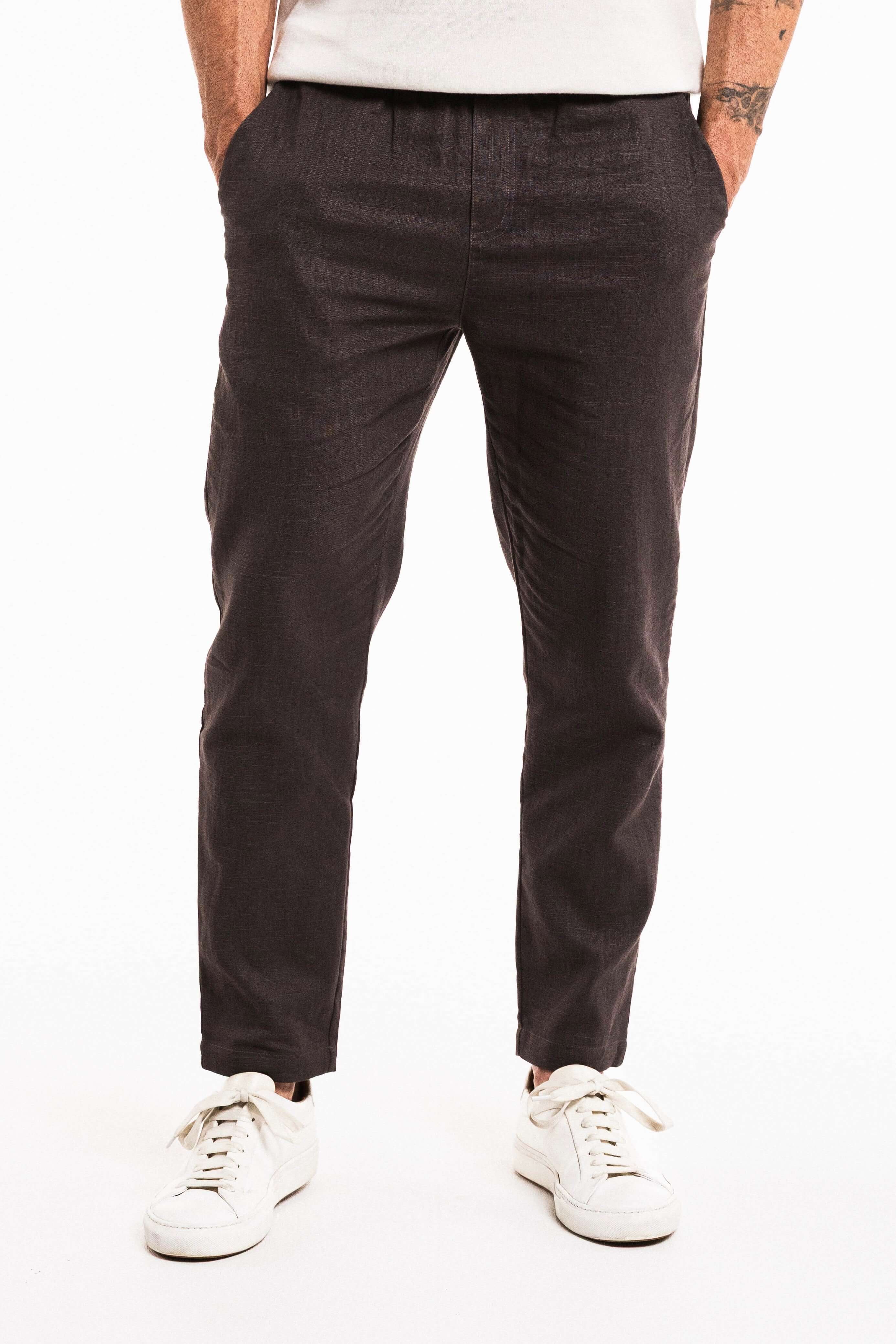 Tailored Lounge Linen Pant in charcoal with elasticated waistband and straight-leg cut, worn with casual white sneakers.