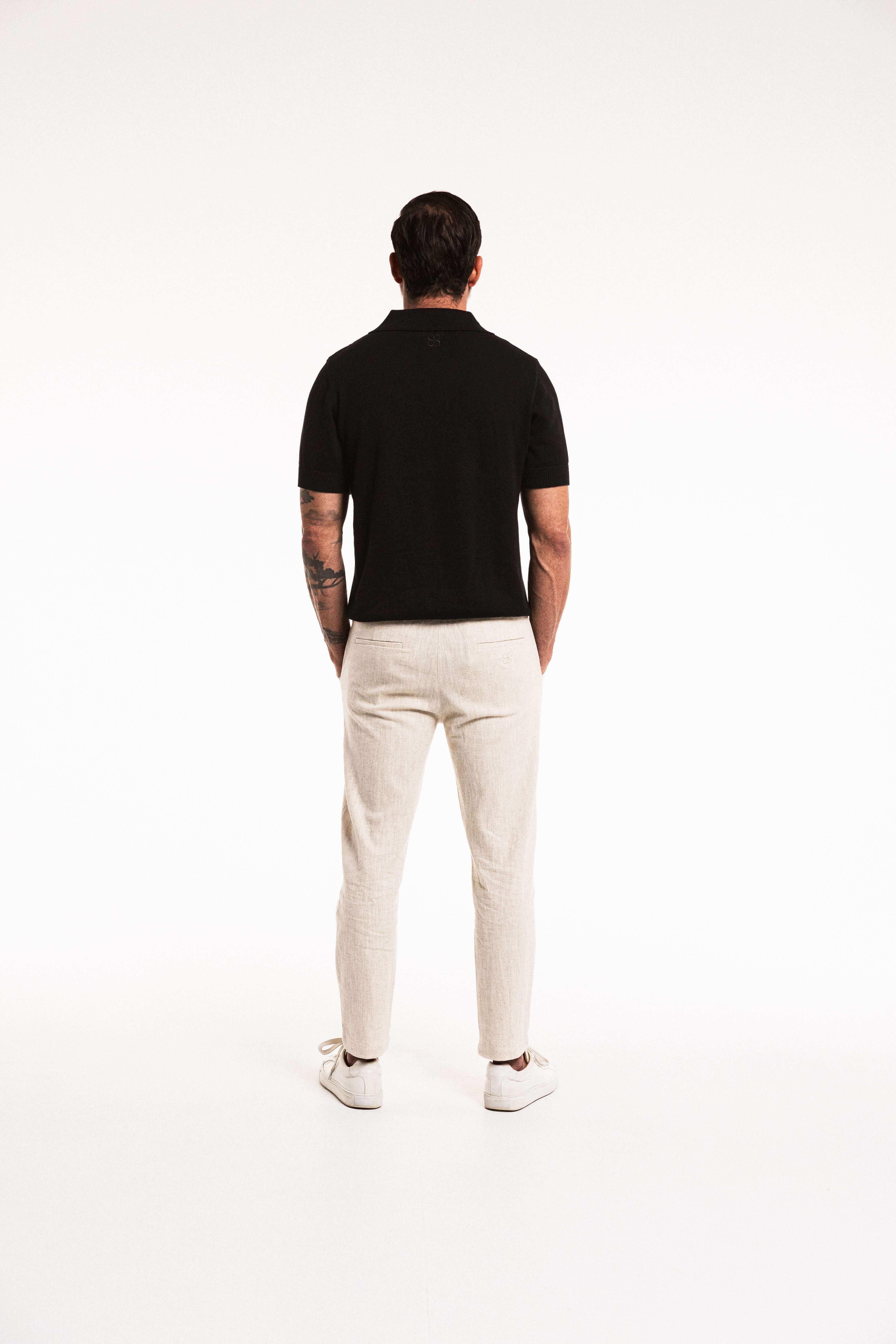 Man wearing Classic Cotton Knit Polo in Obsidian, paired with light pants, showcasing a refined back view.