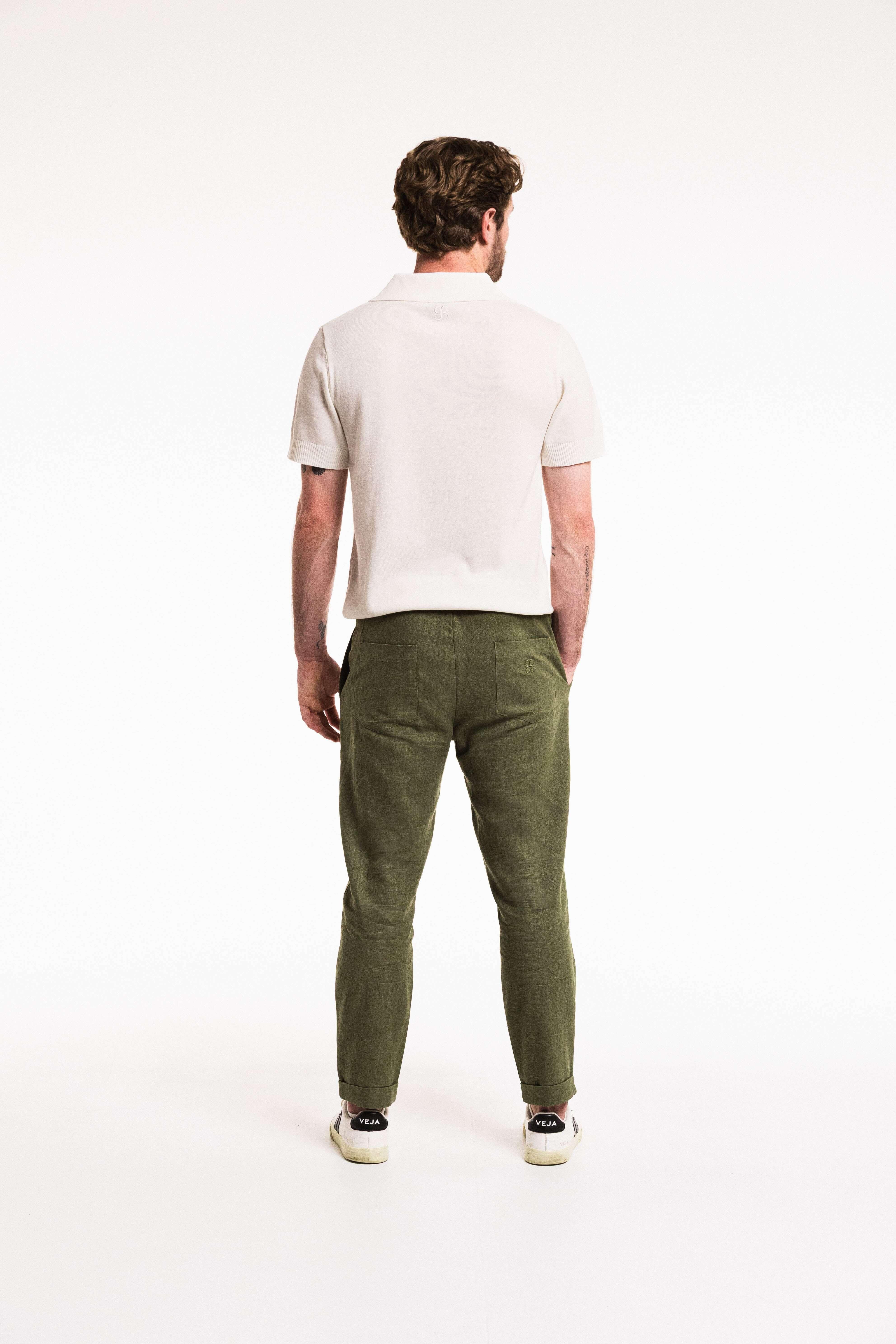 Back view of a man wearing Pleat Cuff Linen Trouser in Olive, paired with a stylish white polo shirt.