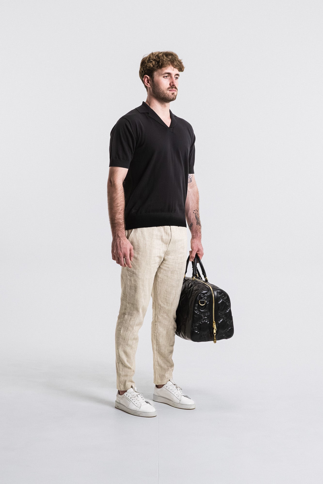 Man holding a black duffel bag against a white background