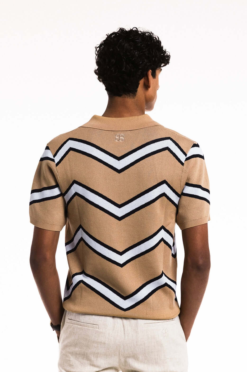Back view of a man wearing a Chevron Zigzag Polo in caramel color with bold chevron stripes.