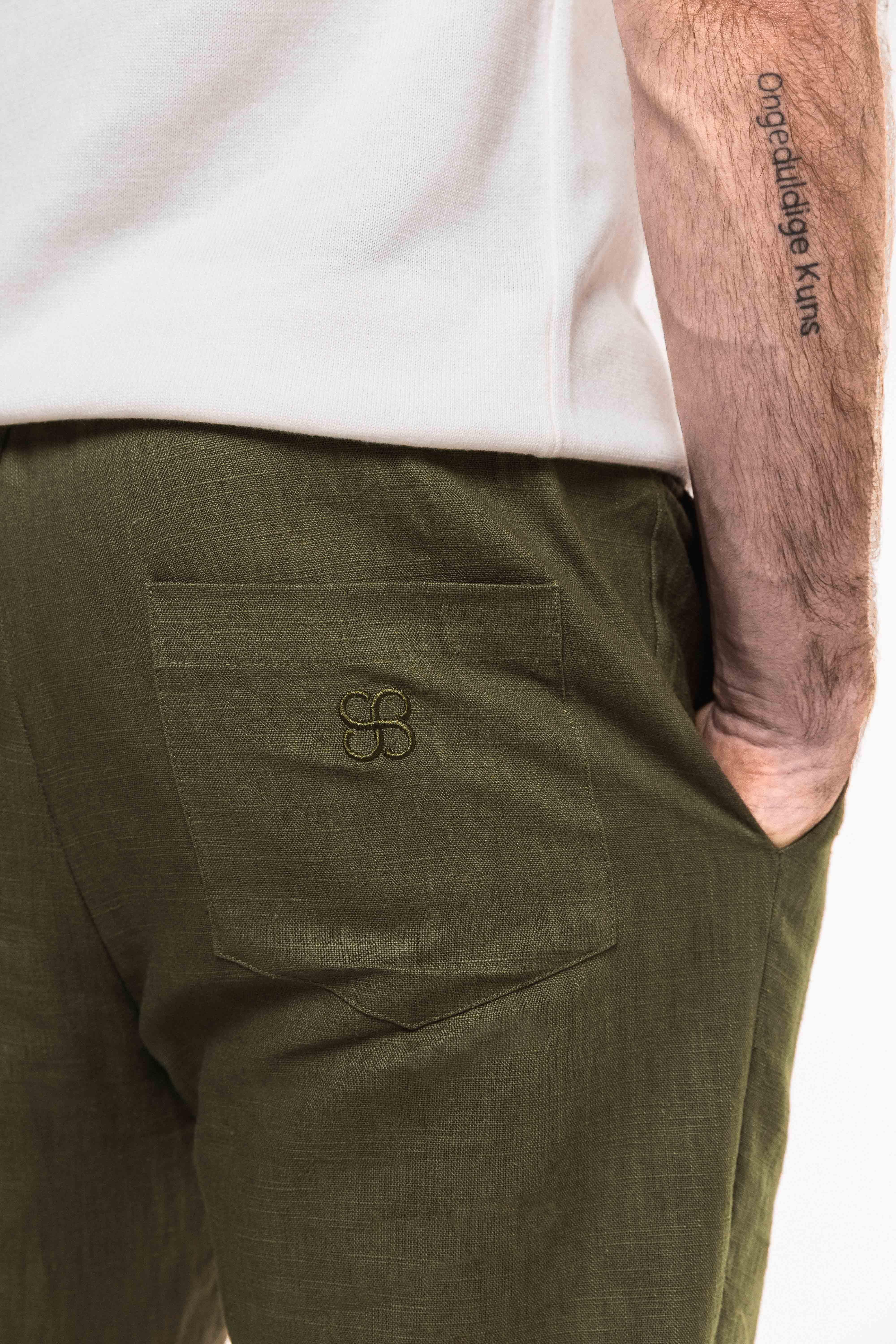 Close-up of the Pleat Cuff Linen Trouser in Olive, showcasing functional back pocket detail and tailored design.