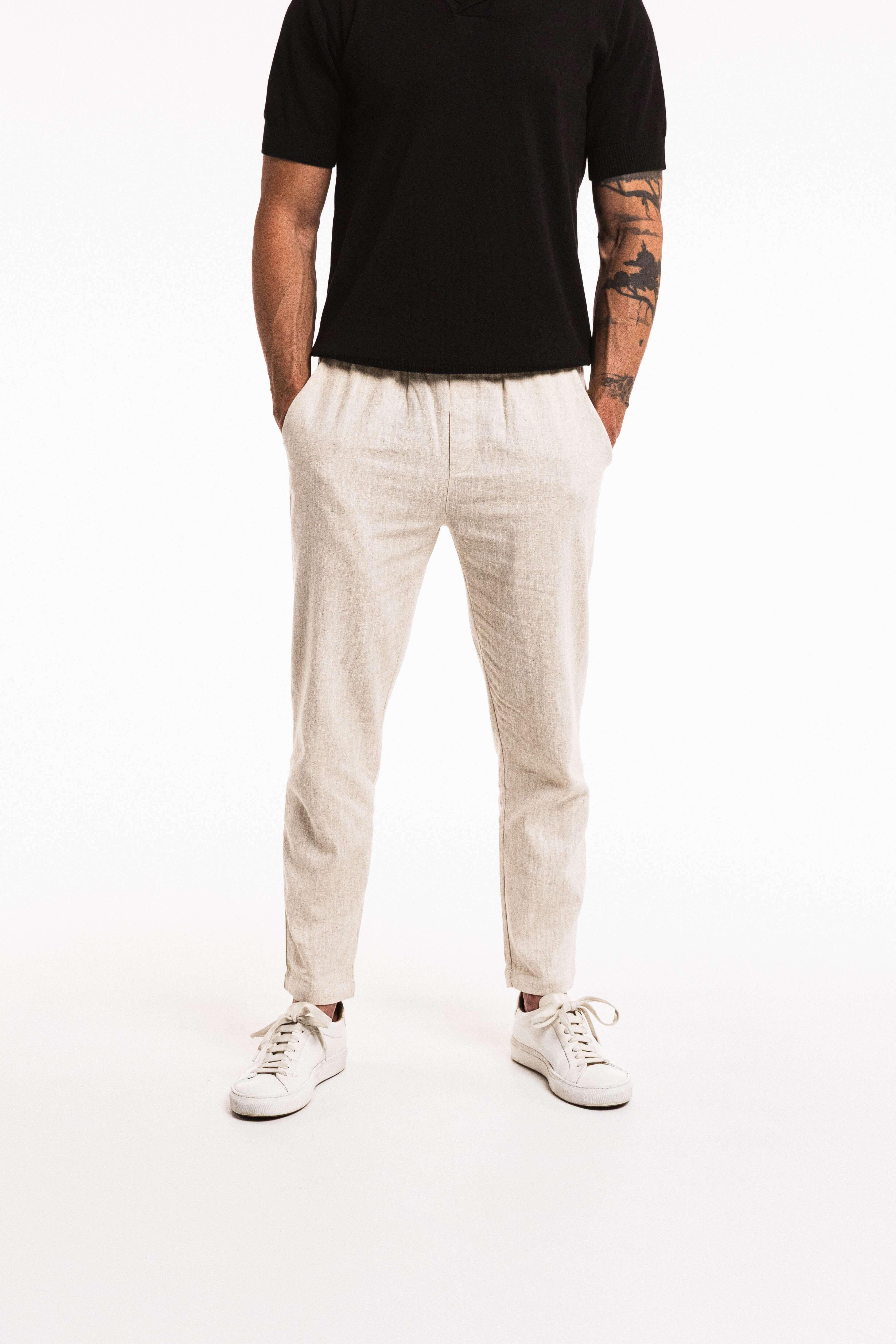 Person wearing a black t-shirt, white pants, and white sneakers on a white background