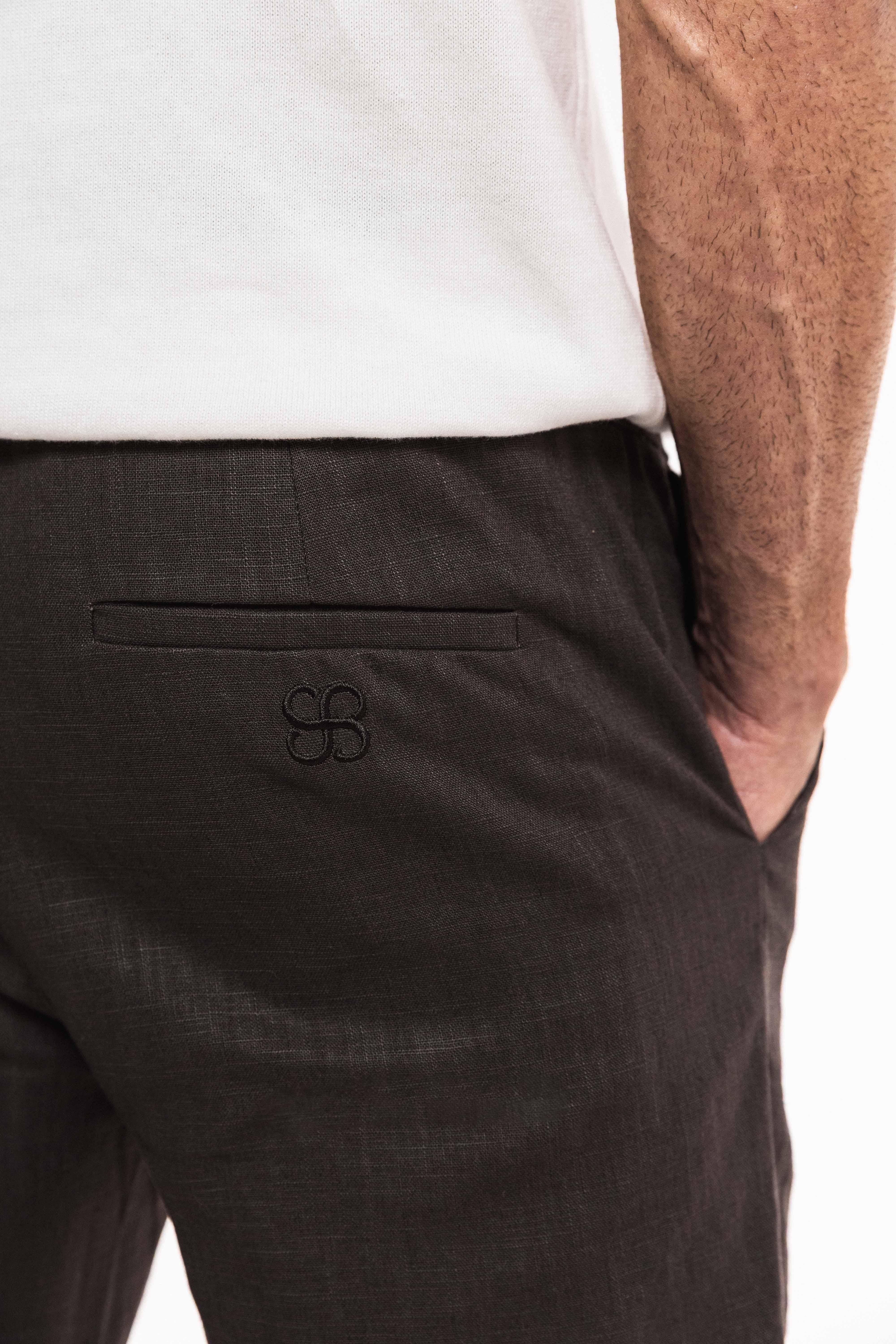 Tailored Lounge Linen Pant back view showcasing pocket and embroidered detail on charcoal linen.