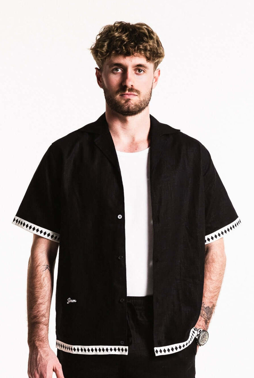 Man wearing a relaxed Diamond Trim Linen Shirt with camp collar and diamond trim details.