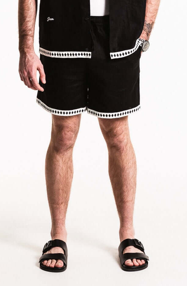 Model wearing Diamond Trim Linen Shorts featuring contrasting woven hem and side pockets.