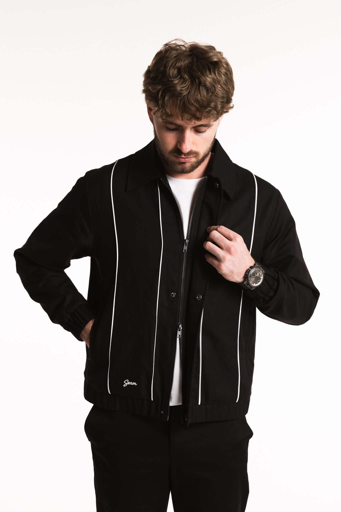 Cotton Contrast Jacket in Black with white piping, worn by a man adjusting the collar, showcasing modern style and comfort.