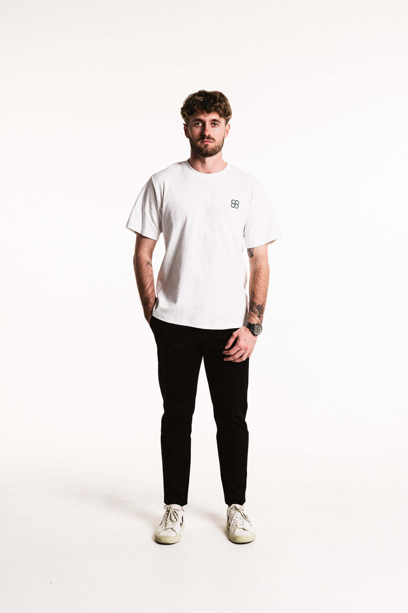 Cotton Typeface T-Shirt in white modeled by a young man, featuring a minimal monogram emblem and oversized branding on the back.