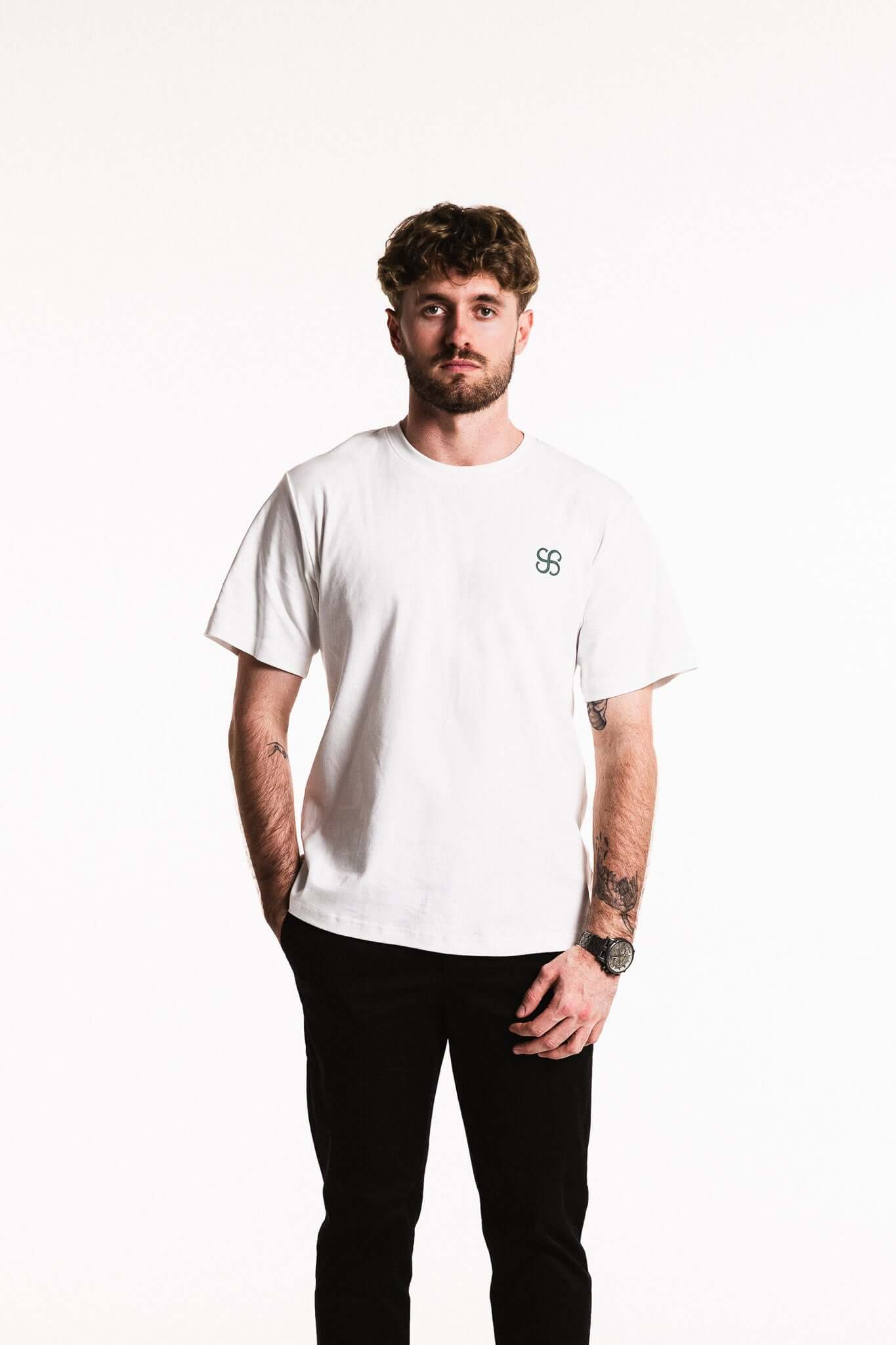 Man wearing a Cotton Typeface T-Shirt in White with a discreet monogram emblem on the chest.