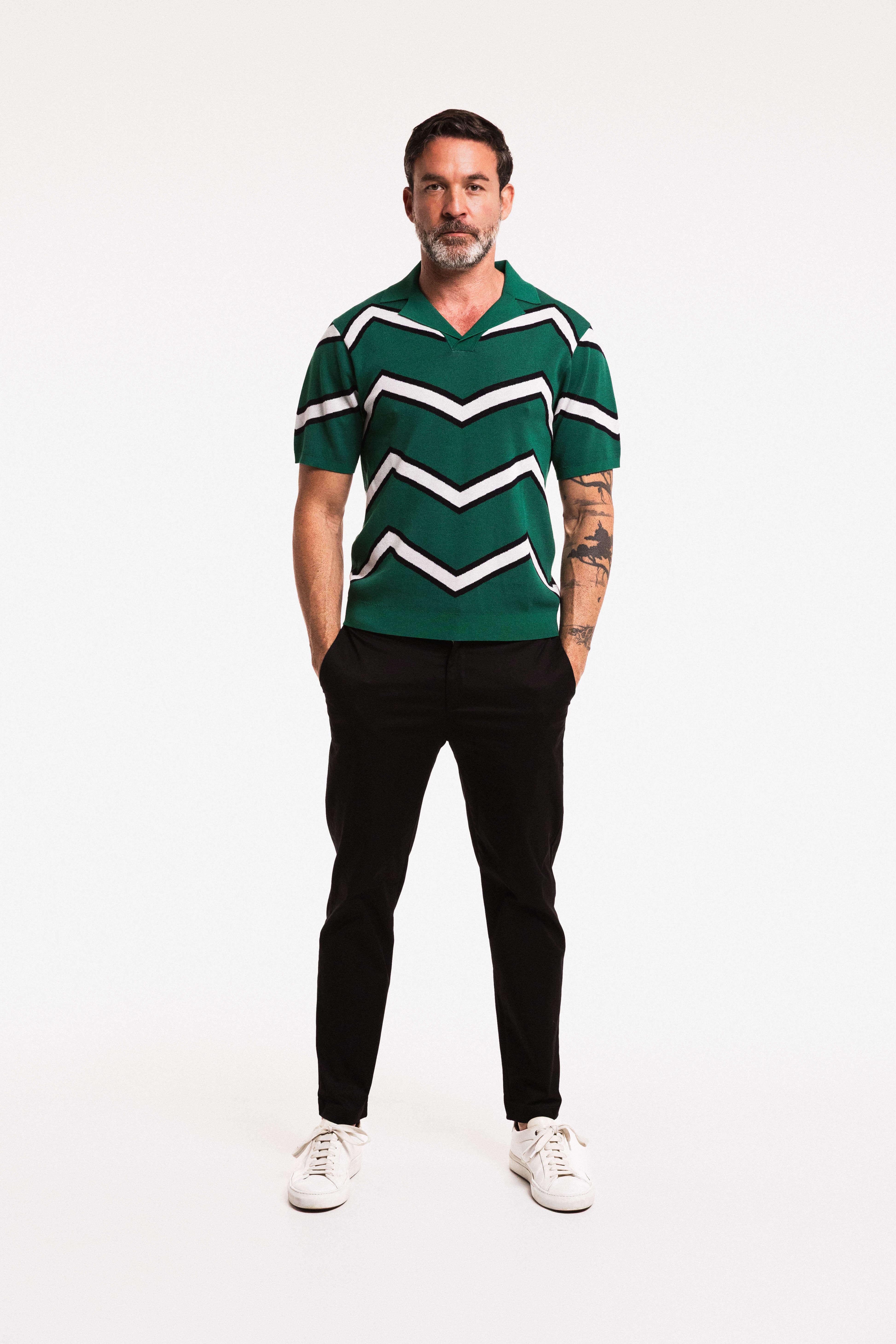Model wearing a Chevron ZigZag Polo in Forest Green with black pants and sneakers, showcasing its bold zigzag design.