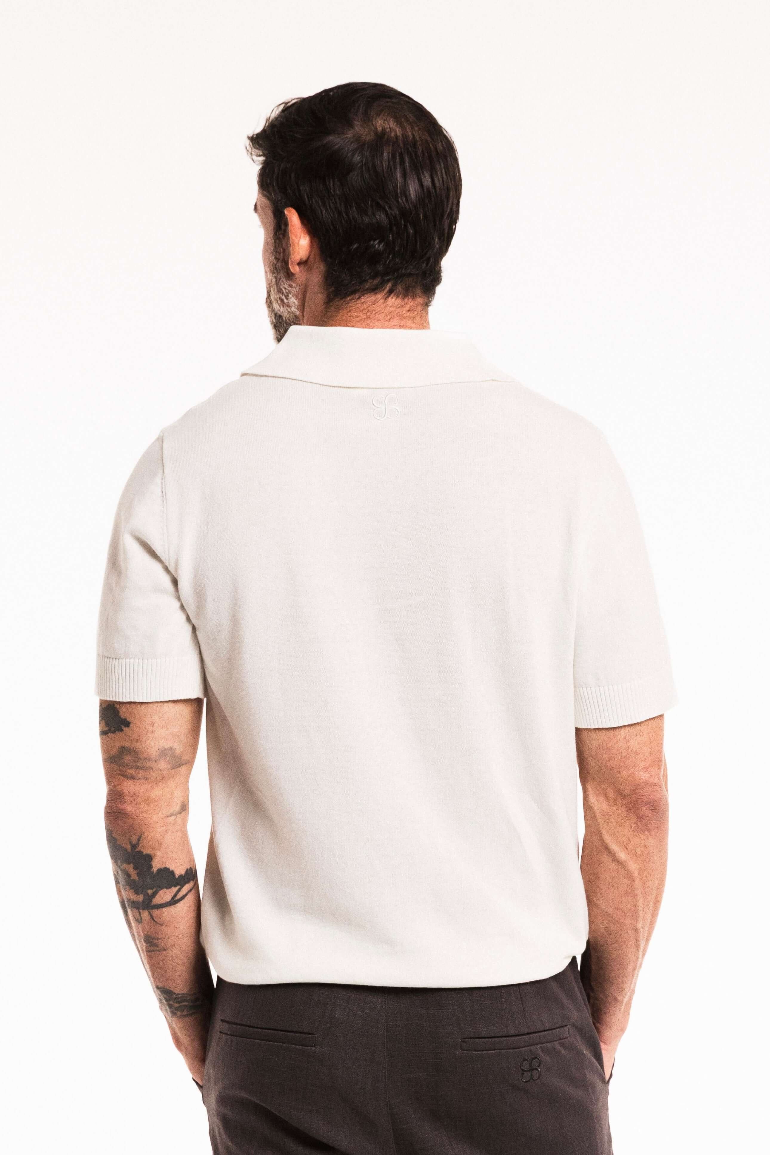Man wearing a Classic Cotton Knit Polo in Ivory, showing the back view with a clean silhouette and traditional collar.