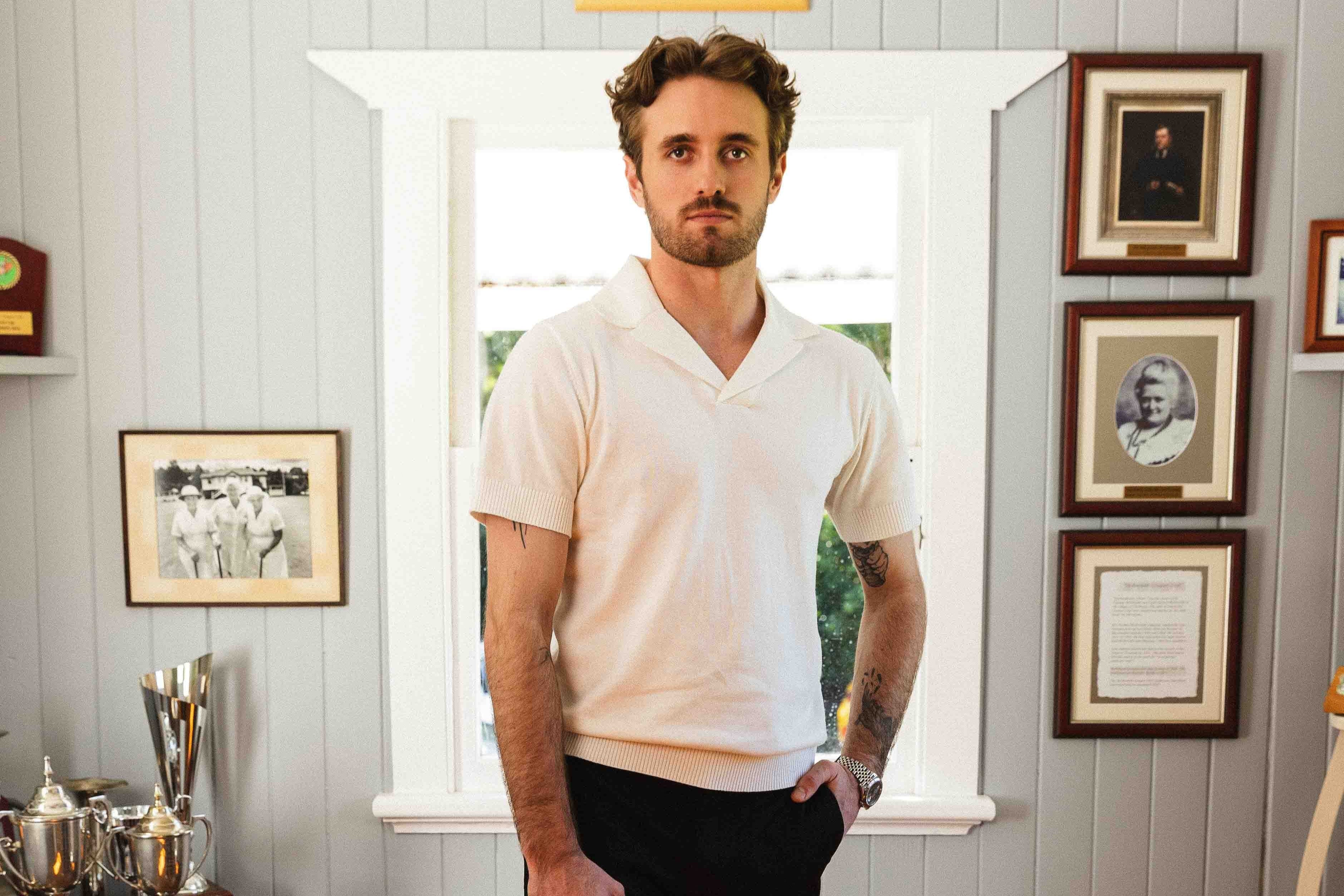 Man standing in a room with framed pictures on the wall