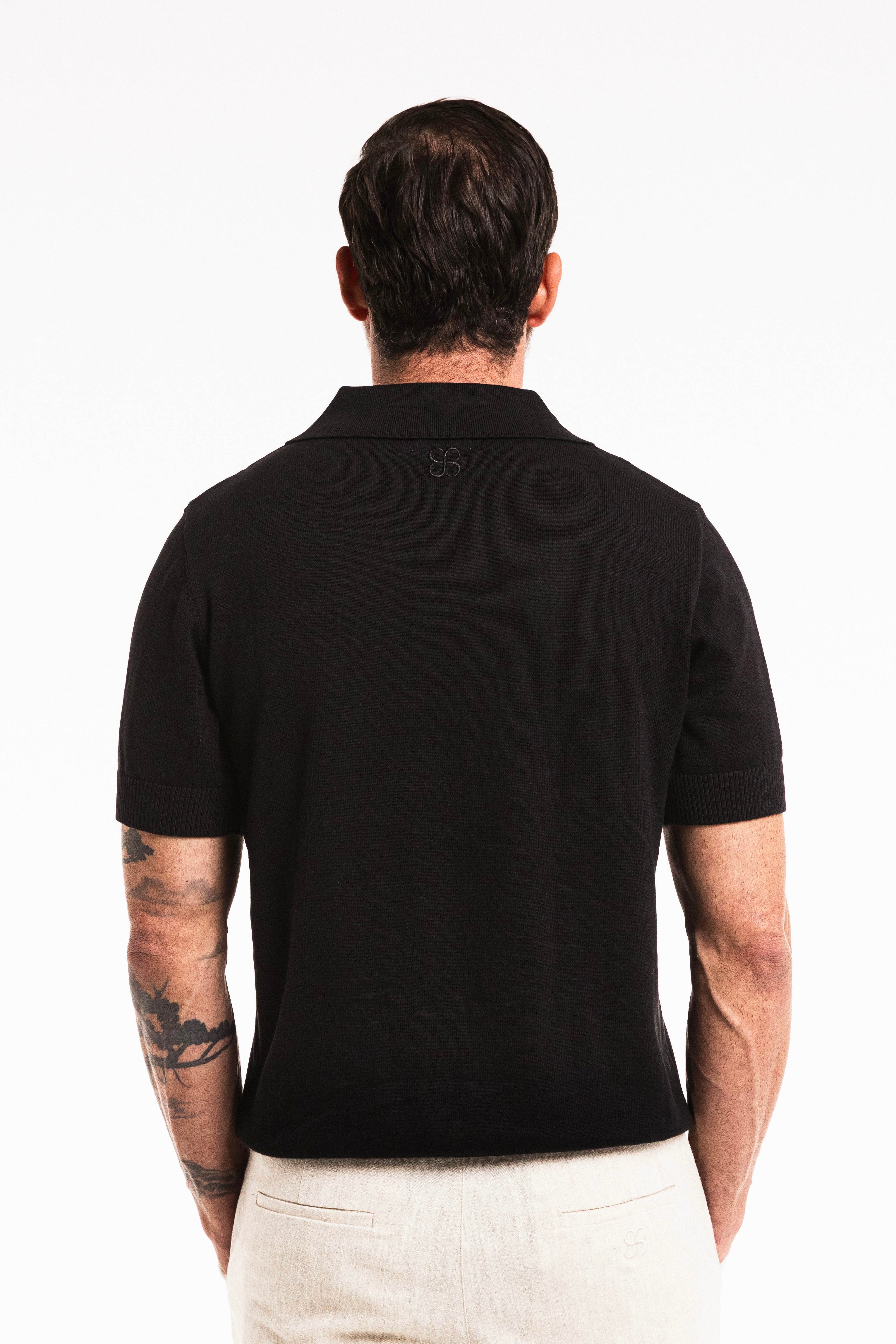 Back view of a model wearing the Classic Cotton Knit Polo in Obsidian with a traditional polo collar.