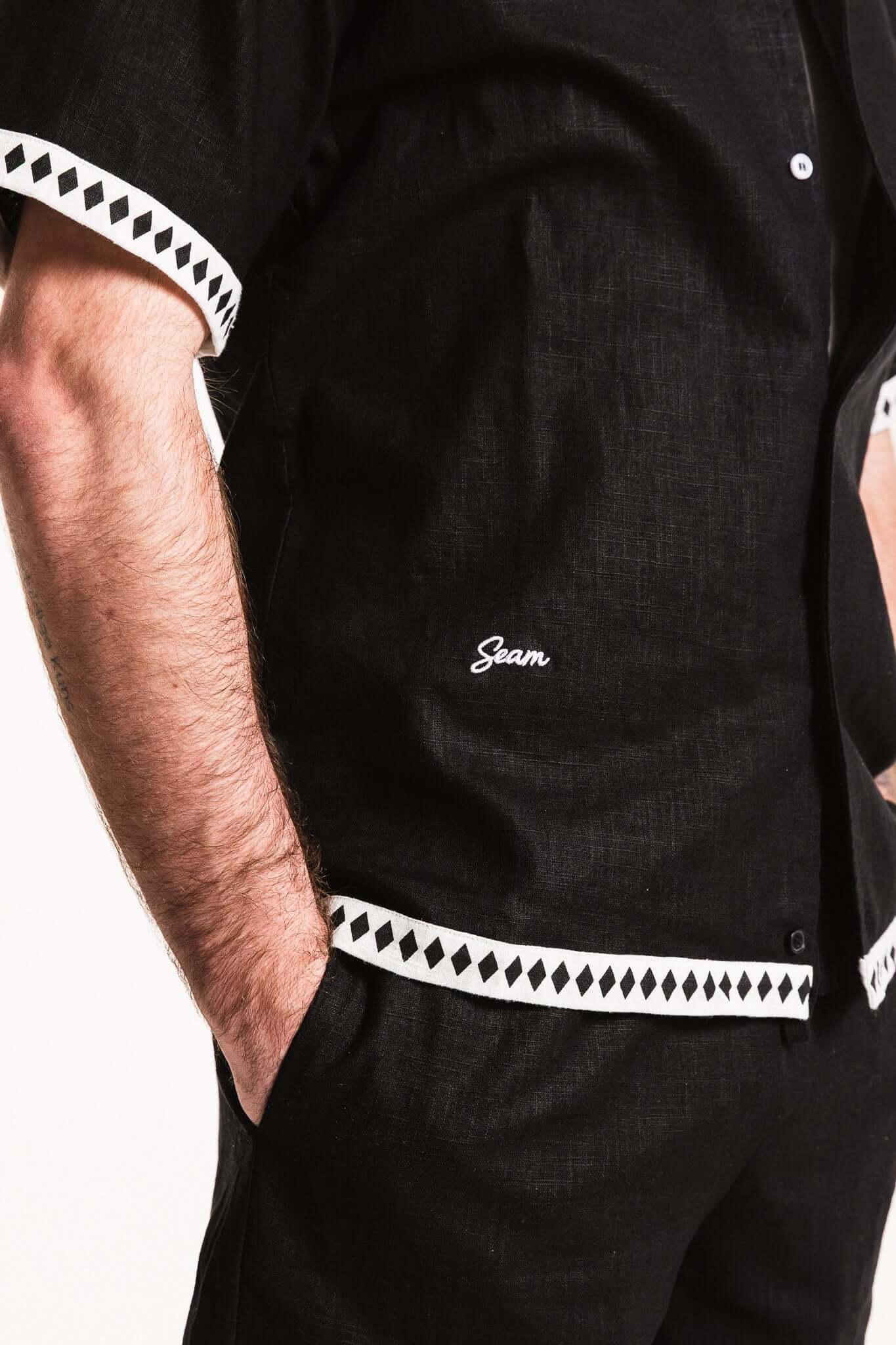 Close-up of the Diamond Trim Linen Shirt showcasing black fabric, contrast diamond trim, and subtle SEAM embroidery.