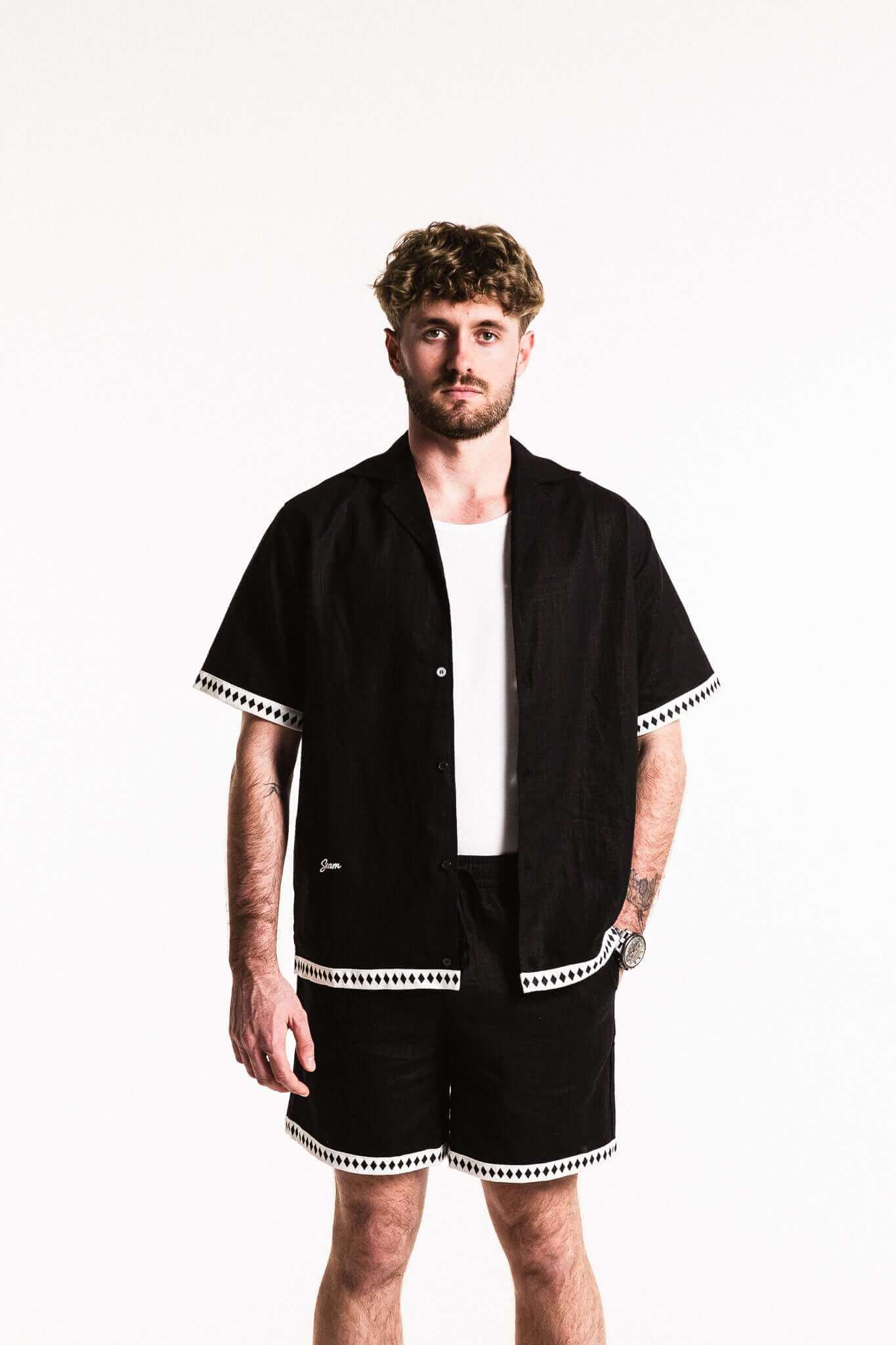 Man wearing a Diamond Trim Linen Shirt with contrasting diamond trim and boxy fit for relaxed sophistication.