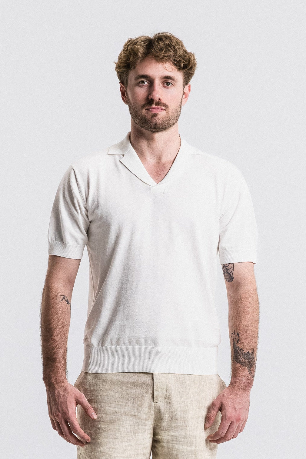 Man wearing a white shirt and beige shorts against a plain background